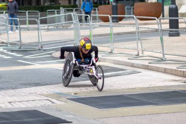 A dedicated athlete competes in a marathon using a racing wheelchair on city streets.